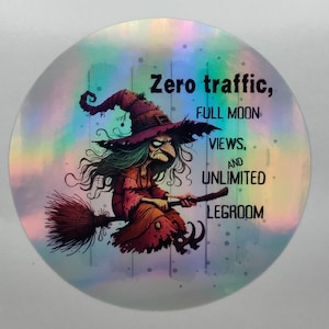 Könnte beinhalten: Ein runder, holografischer Aufkleber mit einer Cartoon-Hexe auf einem Besen. Die Hexe trägt einen lila Hut und ein rotes Kleid. Der Text lautet: "Zero traffic, FULL MOON VIEWS, AND UNLIMITED LEGROOM."