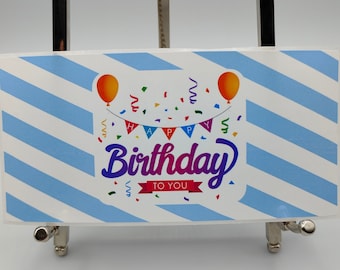 Può includere: Un biglietto a strisce blu e bianche con il testo "Buon compleanno a te" in lettere colorate. Il biglietto presenta una torta di compleanno con due palloncini e coriandoli.