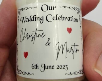 May include: A small white candle with a label that reads "Our Wedding Celebration Christine & Martin 6th June 2023". The label has two red hearts.