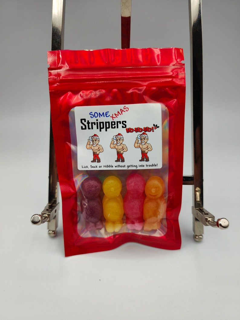 K&ouml;nnte beinhalten: Ein wiederverschlie&szlig;barer Beutel aus rotem Material mit einem Sichtfenster, in dem vier bunte Gummib&auml;rchen in Menschenform zu sehen sind. Der Beutel tr&auml;gt ein Etikett mit der Aufschrift "Some Xmas Strippers" mit einem Comic-Weihnachtsmann und den Worten "Ho-Ho-Ho!" Der Aufkleber tr&auml;gt au&szlig;erdem die Aufschrift "Lick, Suck or Nibble without getting into trouble!"