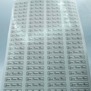 May include: A sheet of white paper with multiple rows of rectangular labels. Each label has the text "Your Name Here" printed in black cursive font.