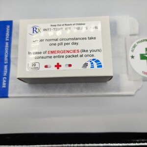 Może przedstawiać: Białe pudełko z niebieskimi i czerwonymi akcentami. Pudełko zawiera lek o nazwie "ANTI-TIGHT GIT TABLETS 16". Etykieta głosi "Keep Out of Reach of Children" i "W nagłych wypadkach (jak w twoim przypadku) zażyj cały zestaw naraz."