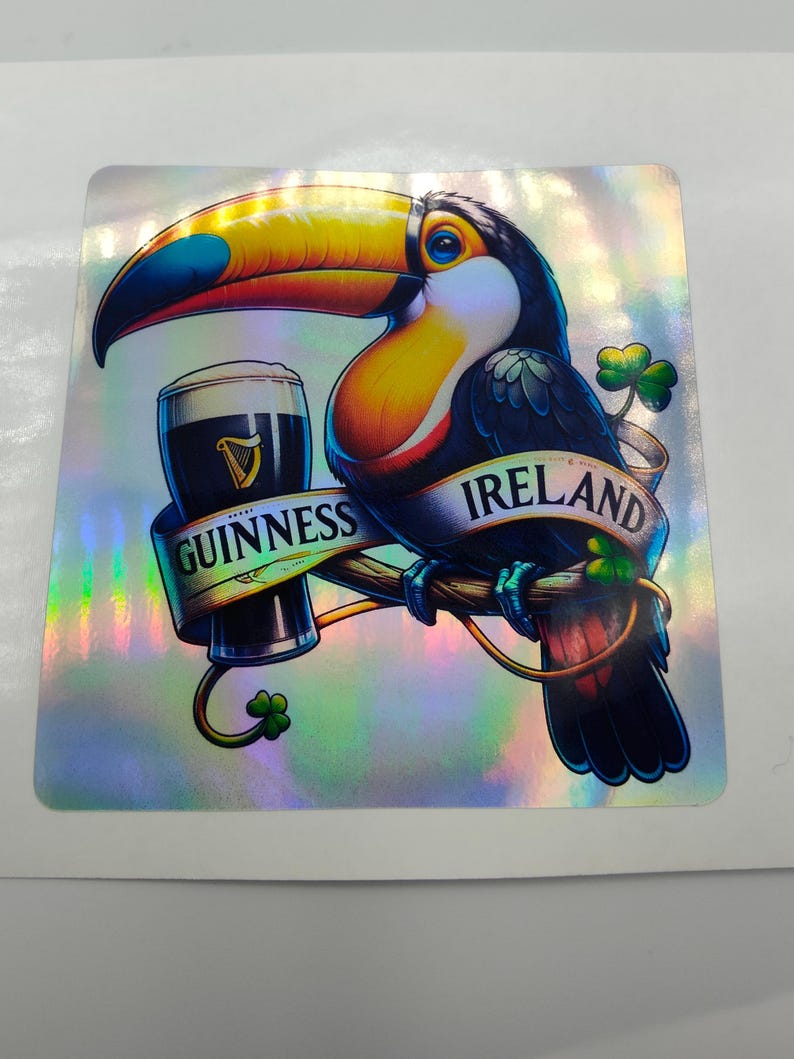 Op de afbeelding: Een toekan met een blauwe en gele snavel houdt een glas Guinness-bier vast. De toekan zit op een tak met een banner waarop "GUINNESS IERLAND" staat.
