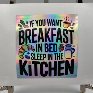 Puede incluir: Pegatina holográfica con el texto "IF YOU WANT BREAKFAST IN BED SLEEP IN THE KITCHEN". La pegatina presenta ilustraciones de un cruasán, arándanos, una fresa, una taza de café y una jarra de leche.