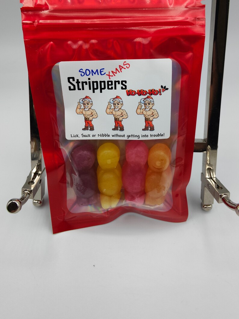 K&ouml;nnte beinhalten: Ein wiederverschlie&szlig;barer roter Beutel mit einem Sichtfenster, in dem bunte Gummib&auml;rchen in Form von Weihnachtsm&auml;nnern zu sehen sind. Der Beutel hat ein Etikett mit der Aufschrift "Some Xmas Strippers" mit einem Bild von drei Weihnachtsm&auml;nnern und dem Text "Ho Ho Ho!"  Das Etikett sagt auch "Lick, Suck or Nibble without getting into trouble!"