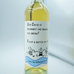 May include: A white wine bottle with a label that reads "Our child is probably the reason you drink! Enjoy a bottle on us. From the O'Donnell family."