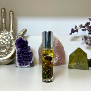 May include: A clear glass roller bottle with a silver cap filled with a yellow liquid and dried herbs and mushrooms.