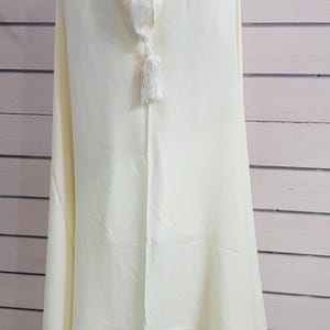 May include: A white hooded robe with a white tassel. The robe is made of a soft, lightweight fabric and has a simple, elegant design.