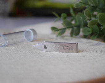 Könnte beinhalten: Silberne Pinzette mit einer spitzen Spitze und dem Text "THE TWEEZERS WITH PIN-POINT-PRECISION", der auf der Seite eingraviert ist.