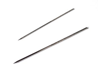Könnte beinhalten: Zwei silberne Werkzeuge aus Metall mit spitzen Spitzen. Das Werkzeug oben ist glatt, während das Werkzeug unten eine strukturierte Oberfläche hat.