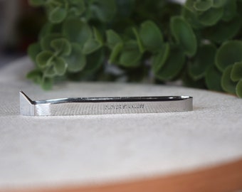 Könnte beinhalten: Ein silbernes Metallwerkzeug mit einer spitzen Spitze und den Worten "CLOVER STAINLESS" eingraviert auf der Seite. Das Werkzeug liegt auf einer hellbraunen Oberfläche.