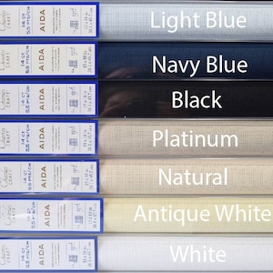 May include: Aida cloth in seven colors: light blue, navy blue, black, platinum, natural, antique white, and white. Each color is labeled with the DMC brand name and the size of the cloth: 14 count, 5.5 stitches per centimeter.
