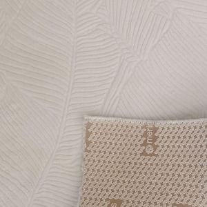 May include: A white rug with a textured leaf pattern. The rug has a brown backing with the word "merinos" printed on it.