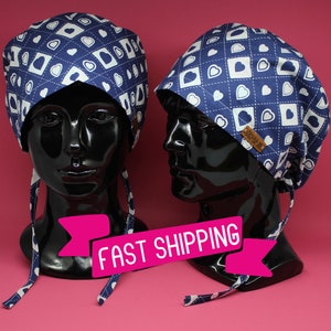 May include: Two blue and white patterned surgical caps with white hearts and a white stitched design. The caps have ties on the back. The caps are on black mannequins with the text "FAST SHIPPING" in a pink banner.