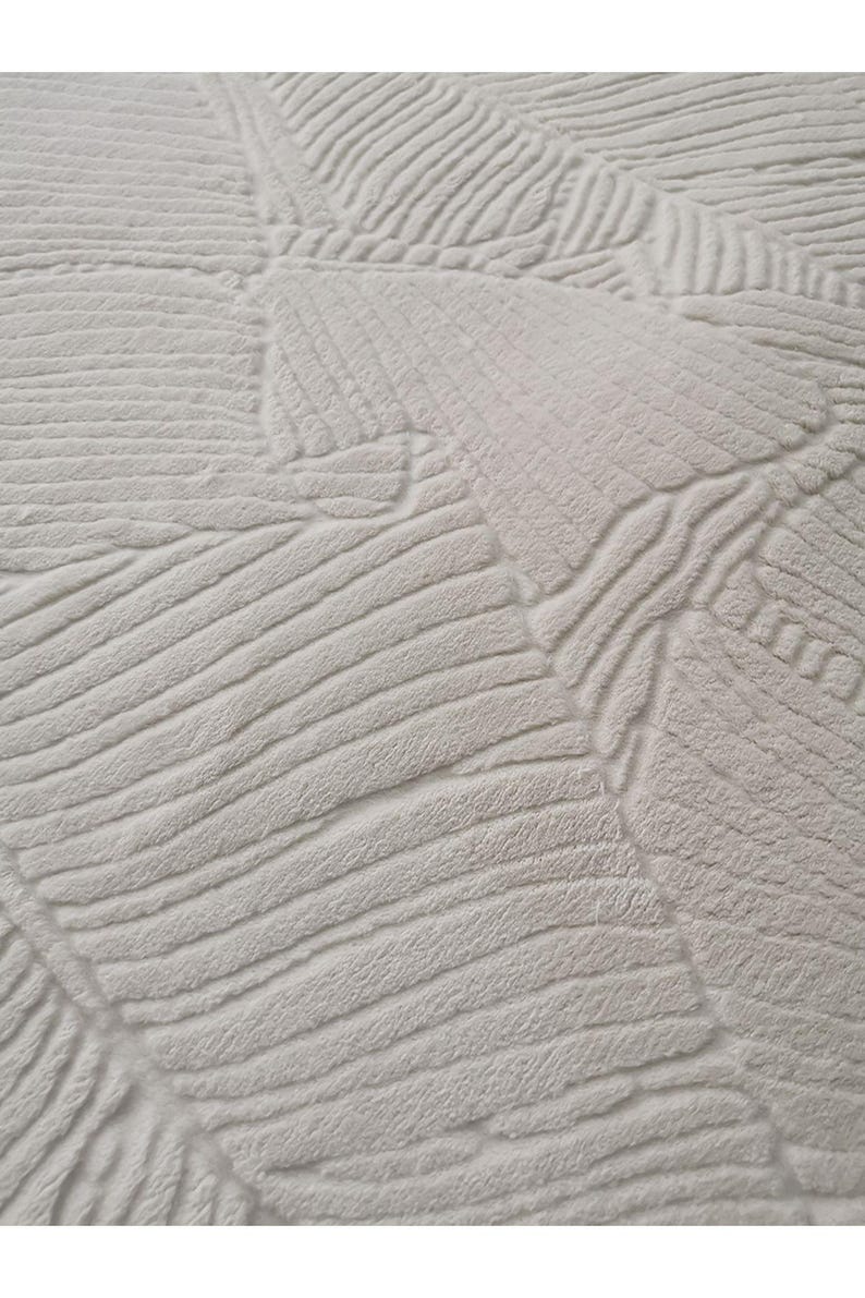 May include: White fluffy rug with a textured pattern of overlapping lines and curves.