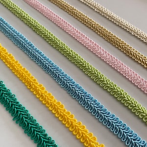 May include: A close-up of seven different colored trim cords. The cords are arranged in a row from left to right, with the colors being green, yellow, blue, light green, pink, beige, and white.