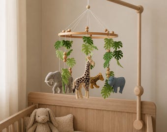 May include: A wooden baby mobile featuring felt animal figures of a giraffe, leopard, elephant, and rhino, with green leaf accents. The mobile hangs above a wooden crib with a stuffed bunny and pillow.