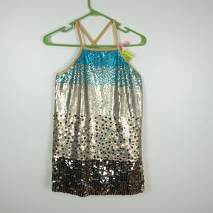 May include: A halter-style top with a gradient of sequins. The top transitions from turquoise to silver and then to brown sequins. It hangs on a green hanger with a tag attached.
