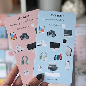 May include: Two blue and pink cards with the text "tech fund saving challenge" and a list of tech items. Each item is worth a certain amount of money. The cards are used to track savings goals.