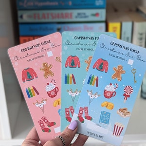 May include: Three Christmas Eve Box cards in pink, teal, and blue, each with festive illustrations including a sweater, gingerbread man, and socks. The cards have the text "Christmas Fund" and "Christmas Eve Box".