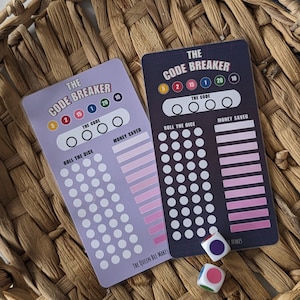 May include: Two "The Code Breaker" game cards with dice, set in a woven basket. The cards are purple and navy blue, featuring white circles and pink gradients. Text includes "Roll the Dice" and "Money Saved".