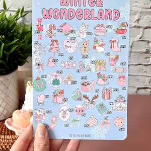 May include: A light blue sticker sheet with the words "Winter Wonderland" in pink. The sheet features various winter-themed illustrations, including a nutcracker, candy canes, and gift boxes. The text "The Queen Bee Makes" is at the bottom.