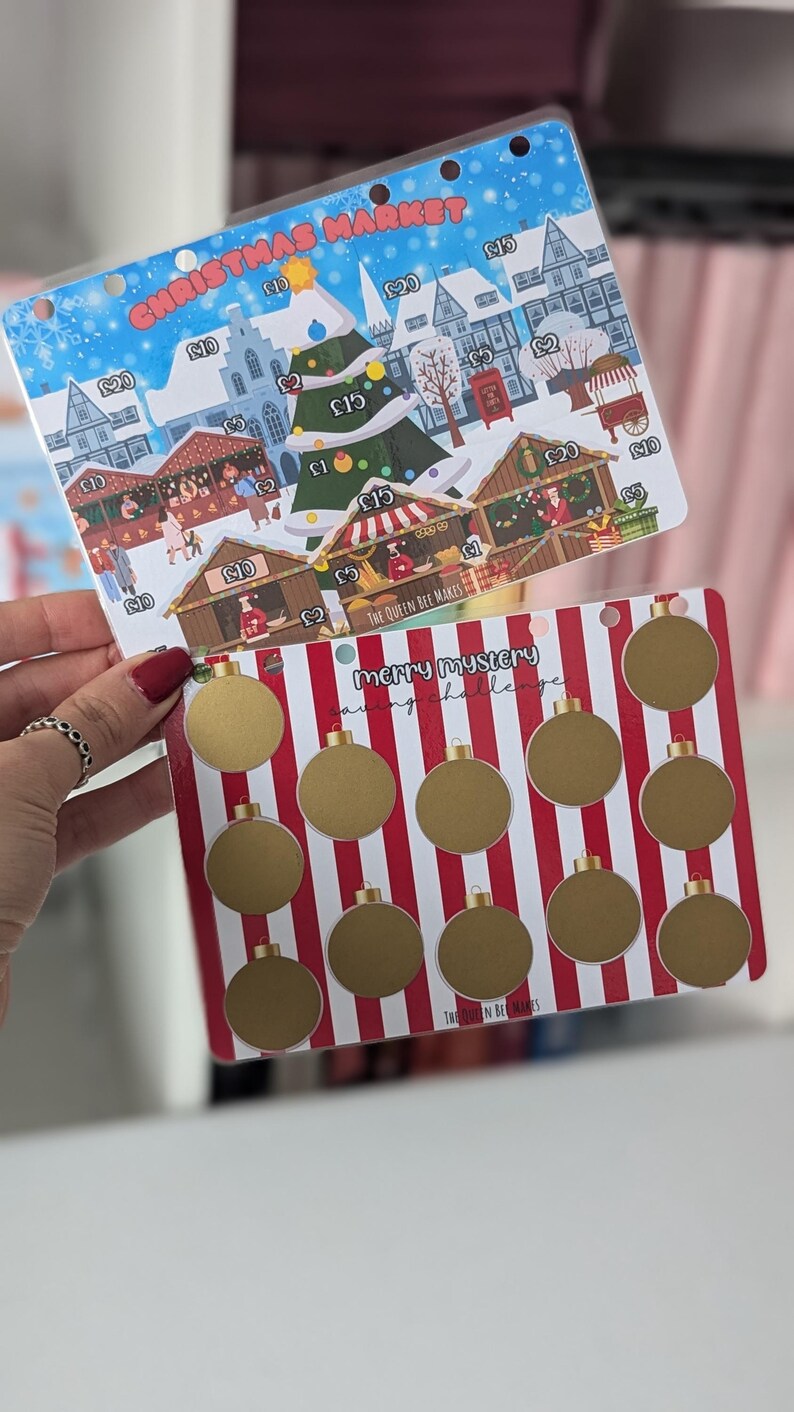 May include: A Christmas market themed savings challenge card with a red and white striped background and gold circles. The text "Merry Mystery Saving Challenge" is printed on the card.