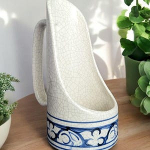 May include: A white ceramic mug with a blue and white floral design. The mug has a crackled glaze and a handle.