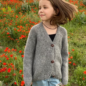 さまざまな色とサイズの子供用オーバーサイズのゆったりしたカーディガン。厚手のニットで男女兼用のセーター。手編みの幼児用カーディガン セーター。
