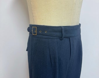 May include: Dark blue pleated pants with a brown leather belt and a gold buckle. The pants have a herringbone pattern.