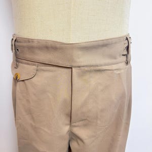 Puede incluir: Pantal&oacute;n beige con cintura ancha y cierre de bot&oacute;n. El pantal&oacute;n tiene un solo bolsillo delantero.