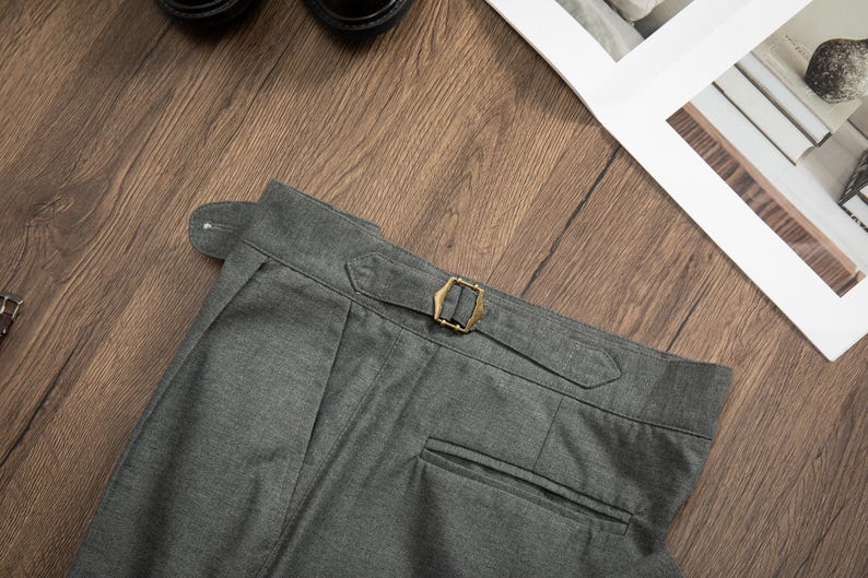 K&ouml;nnte beinhalten: Graue Wollhose mit einer einzigen Ges&auml;&szlig;tasche und einer Messing-Schnalle am Bund.