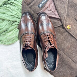 May include: A pair of brown leather lace-up shoes with brogue detailing. The shoes have a classic design and are perfect for formal occasions.