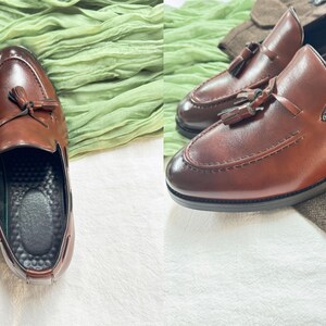 May include: Two pairs of brown leather tassel loafers. The loafers have a pointed toe and a slip-on design.