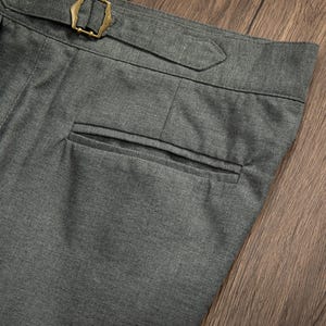 K&ouml;nnte beinhalten: Graue Wollhose mit einer einzigen Ges&auml;&szlig;tasche und einem G&uuml;rtelschlaufen-Detail.