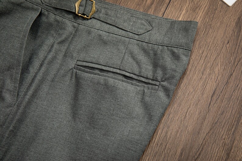 K&ouml;nnte beinhalten: Graue Wollhose mit einer einzigen Ges&auml;&szlig;tasche und einem G&uuml;rtelschlaufen-Detail.
