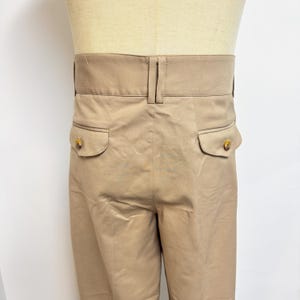 Puede incluir: Un pantal&oacute;n beige con dos bolsillos traseros y cierre de bot&oacute;n. El pantal&oacute;n tiene una pierna recta y un ajuste holgado.