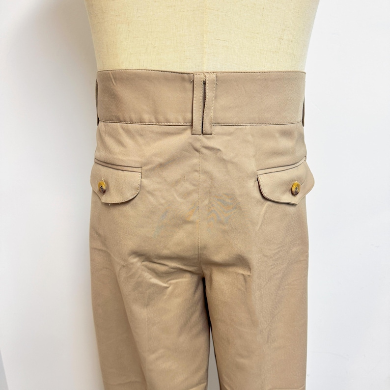 Puede incluir: Un pantal&oacute;n beige con dos bolsillos traseros y cierre de bot&oacute;n. El pantal&oacute;n tiene una pierna recta y un ajuste holgado.