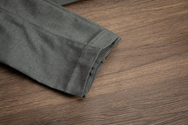 K&ouml;nnte beinhalten: Nahaufnahme einer grauen Hose, die in der H&auml;lfte gefaltet ist und die Textur des Stoffes und den Saum zeigt.