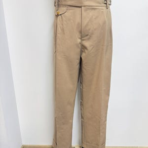 Puede incluir: Un pantal&oacute;n beige de cintura alta con cintur&oacute;n y cierre de bot&oacute;n. El pantal&oacute;n tiene un corte holgado y est&aacute; hecho de una tela ligera.