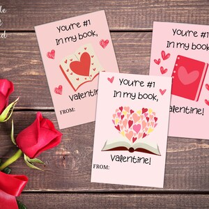 Op de afbeelding: Drie roze Valentijnsdagkaarten met de tekst "You're #1 in my book" en een boekillustratie. De kaarten hebben verschillende boekillustraties en de tekst "Valentine!" onderaan.