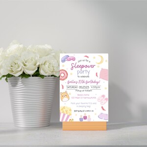 K&ouml;nnte beinhalten: Eine rosa und wei&szlig;e Einladungskarte mit einem Comic-Donut, einer Schlafmaske und einem Kissen. Der Text auf der Karte lautet: "Schlie&szlig;en Sie sich uns zu einer Pyjamaparty an, um Bellas 10. Geburtstag zu feiern! Samstag, 052323, 16:00 Uhr Abholung um 11:00 Uhr Bellas Zuhause 1121 Main St Yarmouth MA Packen Sie Ihren Lieblings-Pyjama und einen Schlafsack ein."