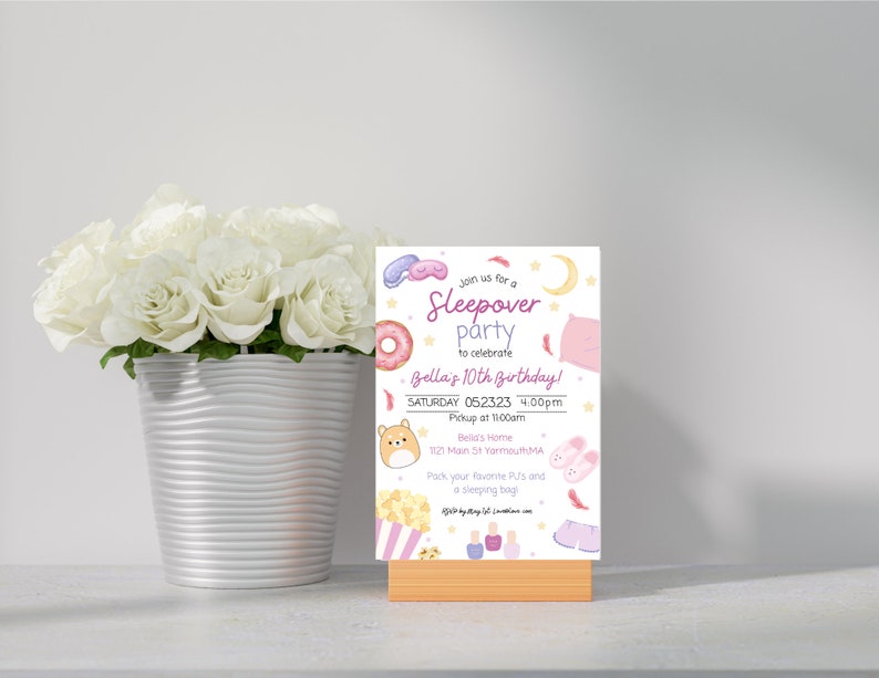 K&ouml;nnte beinhalten: Eine rosa und wei&szlig;e Einladungskarte mit einem Comic-Donut, einer Schlafmaske und einem Kissen. Der Text auf der Karte lautet: "Schlie&szlig;en Sie sich uns zu einer Pyjamaparty an, um Bellas 10. Geburtstag zu feiern! Samstag, 052323, 16:00 Uhr Abholung um 11:00 Uhr Bellas Zuhause 1121 Main St Yarmouth MA Packen Sie Ihren Lieblings-Pyjama und einen Schlafsack ein."