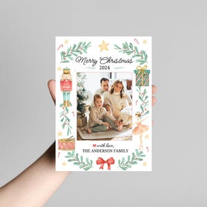 K&ouml;nnte beinhalten: Eine Weihnachtskarte mit einer Aquarell-Illustration einer Familie, einem Nussknacker, einer Ballerina und einem Geschenk. Die Karte lautet "Frohe Weihnachten 2024" und "mit Liebe, Die Familie Anderson".