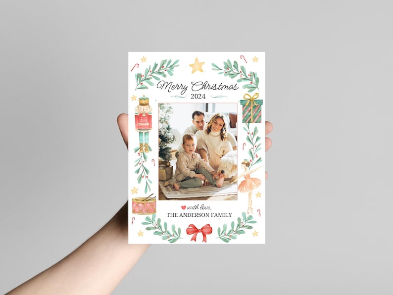 K&ouml;nnte beinhalten: Eine Weihnachtskarte mit einer Aquarell-Illustration einer Familie, einem Nussknacker, einer Ballerina und einem Geschenk. Die Karte lautet "Frohe Weihnachten 2024" und "mit Liebe, Die Familie Anderson".