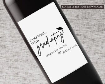 Op de afbeelding: Wit wijnfles etiket met zwarte tekst die "Pairs well with graduating! Congratulations! Kayla & Max" luidt. Een zwart afstudeerhoedje-icoon bevindt zich boven de tekst.