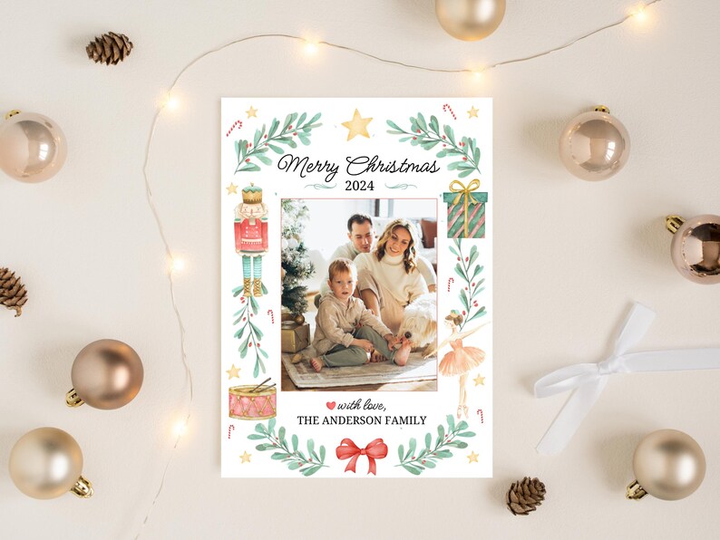K&ouml;nnte beinhalten: Eine Weihnachtskarte mit einer vierk&ouml;pfigen Familie vor einem Weihnachtsbaum. Die Karte hat ein Aquarelldesign mit einem Nussknacker, einer Ballerina, einer Trommel und einer Geschenkbox. Der Text auf der Karte lautet "Frohe Weihnachten 2024" und "mit Liebe, Die Familie Anderson".