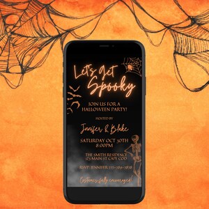 K&ouml;nnte beinhalten: Auf dem Bildschirm eines schwarzen Smartphones ist eine Halloween-Partyeinladung mit orangefarbenem Text zu sehen, der "Let's get Spooky" lautet. Die Einladung enth&auml;lt Details zur Party, einschlie&szlig;lich Datum, Uhrzeit, Ort und Namen der Gastgeber. Der Hintergrund der Einladung ist schwarz mit einem Spinnennetz-Design.