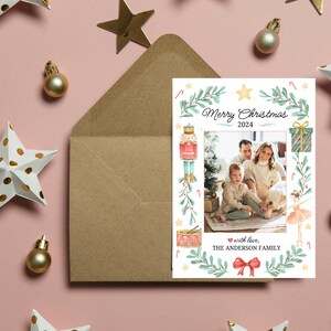 K&ouml;nnte beinhalten: Eine Weihnachtskarte mit einer Aquarell-Illustration eines Nussknackers, einer Ballerina und eines Weihnachtsbaums. Die Karte zeigt ein Familienfoto und den Text "Frohe Weihnachten 2024" und "mit Liebe, DIE FAMILIE ANDERSON".