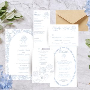May include: A collection of wedding stationery, including invitations, RSVP cards, and menu cards, with a light blue floral design. The invitation features the names "Isabella Smith and Andrew Jones" and the date "07.29.2026". A brown envelope is also included.